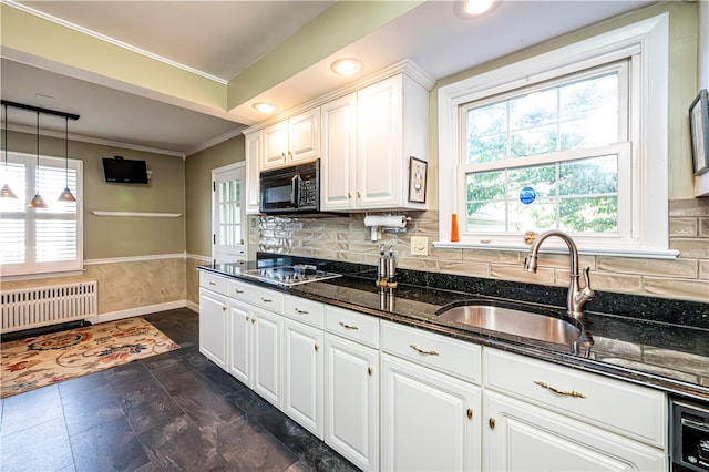 kitchen featuring white cabinets, hanging light fixtures, radiator heating unit, black appliances, and dark stone counters