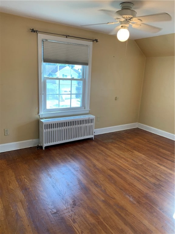 empty room featuring radiator heating unit, vaulted ceiling, ceiling fan, and dark hardwood / wood-style flooring