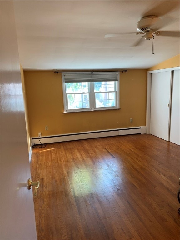 spare room featuring wood-type flooring, baseboard heating, and ceiling fan