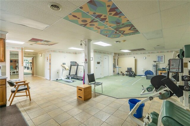 gym featuring a paneled ceiling and light tile patterned floors