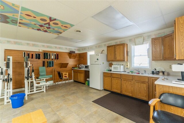 kitchen featuring white appliances, light tile patterned floors, a drop ceiling, and sink