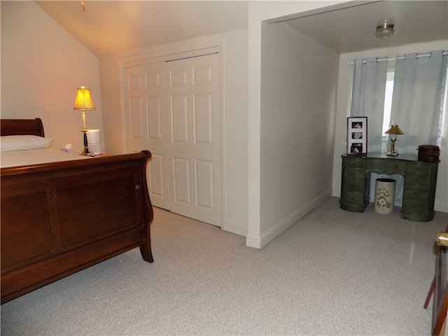 bedroom featuring lofted ceiling, a closet, and light carpet