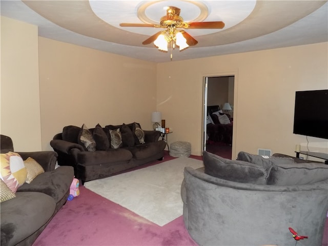 living room featuring a tray ceiling, ceiling fan, and carpet