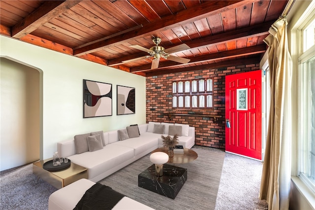 carpeted living room with wood ceiling, brick wall, beam ceiling, and ceiling fan