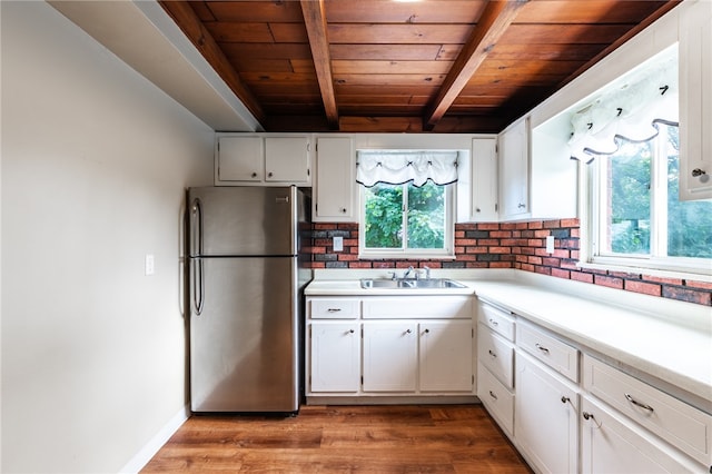 kitchen featuring hardwood / wood-style floors, wood ceiling, beamed ceiling, white cabinetry, and stainless steel fridge