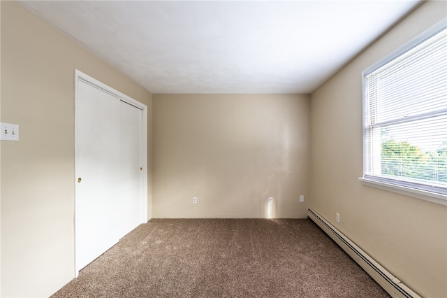 carpeted spare room featuring a baseboard heating unit