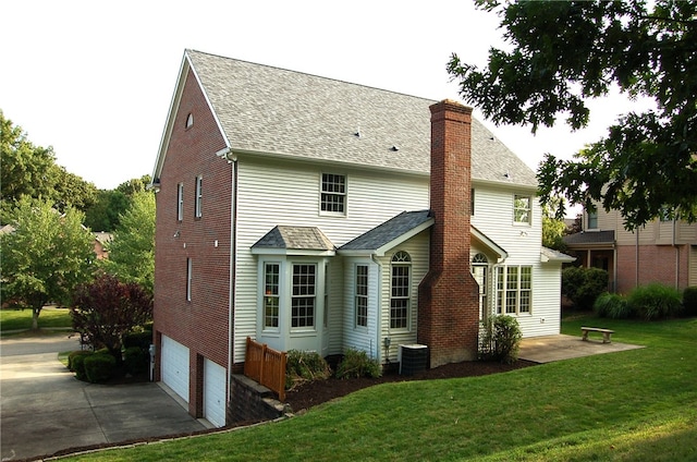 rear view of house featuring a lawn, central AC, and a garage