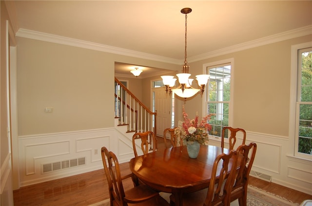 dining area with wood-type flooring, crown molding, and a chandelier