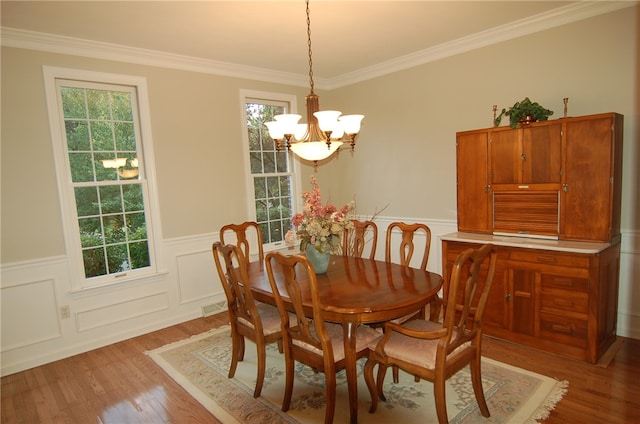 dining space with a notable chandelier, light wood-type flooring, plenty of natural light, and crown molding