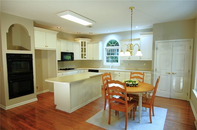 kitchen with a center island, dark wood-type flooring, white cabinets, an inviting chandelier, and black appliances