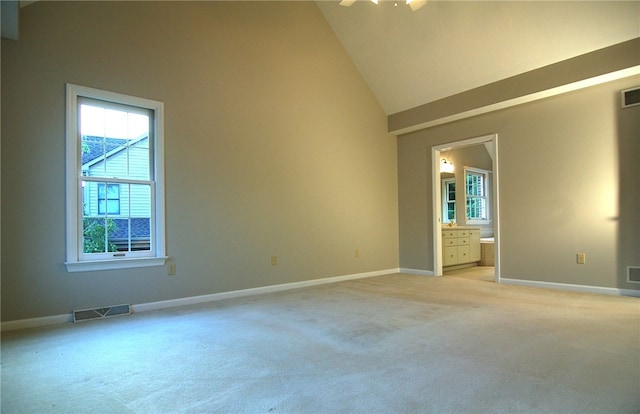 spare room featuring light carpet and high vaulted ceiling