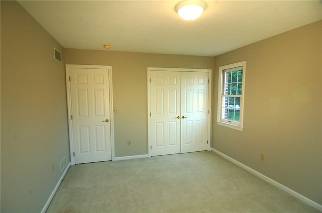 unfurnished bedroom featuring light colored carpet and a closet