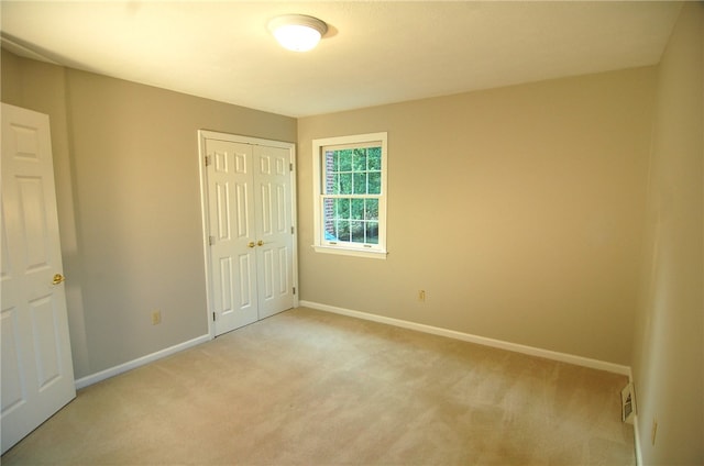 unfurnished bedroom with light carpet and a closet