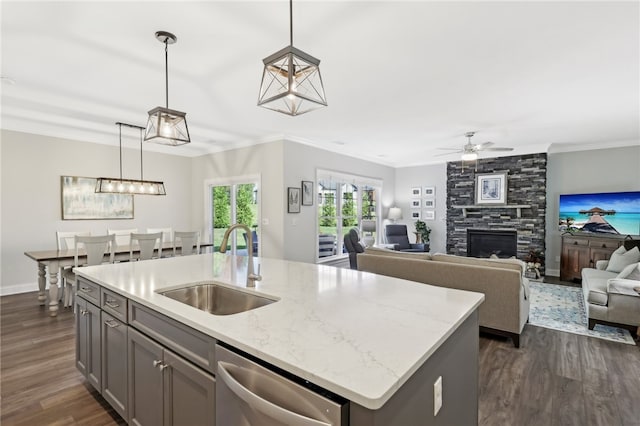 kitchen featuring a large fireplace, dishwasher, sink, dark hardwood / wood-style floors, and a center island with sink