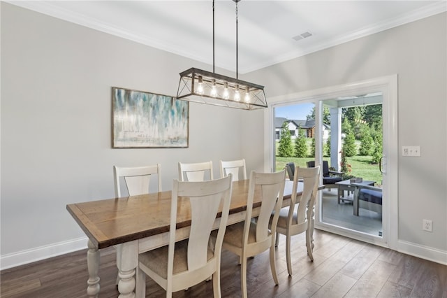 dining room with dark wood-type flooring, a chandelier, and crown molding