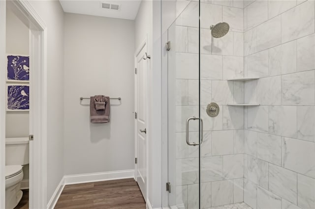 bathroom with a shower with door, toilet, and hardwood / wood-style flooring