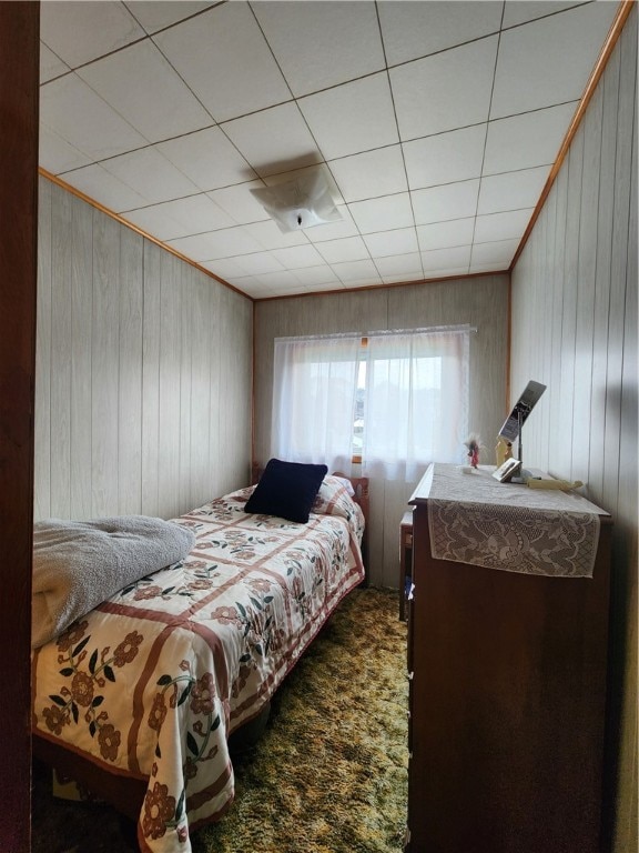 bedroom featuring wood walls and carpet flooring