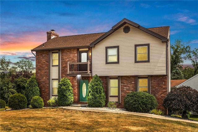 view of front of property featuring a lawn and a balcony