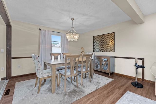 dining space featuring a textured ceiling, a chandelier, and dark hardwood / wood-style floors