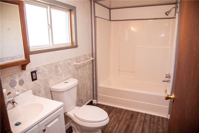 full bathroom featuring vanity, hardwood / wood-style floors, tile walls, toilet, and tub / shower combination