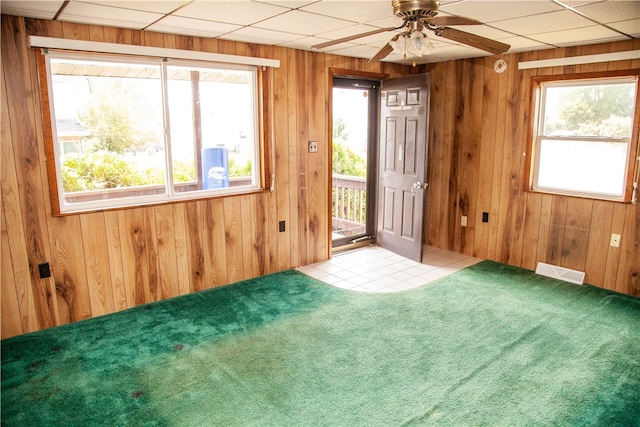 spare room featuring a paneled ceiling, ceiling fan, wood walls, and carpet floors