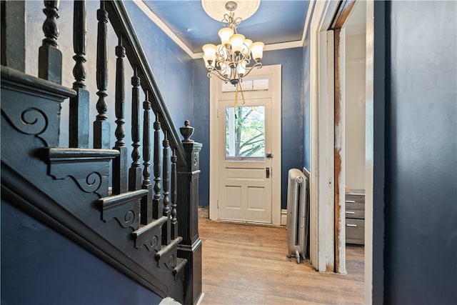 entrance foyer with a notable chandelier, stairway, light wood-type flooring, and radiator