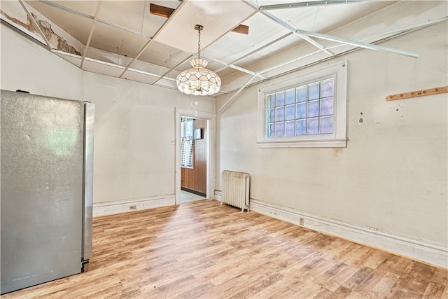 unfurnished room featuring radiator and wood finished floors