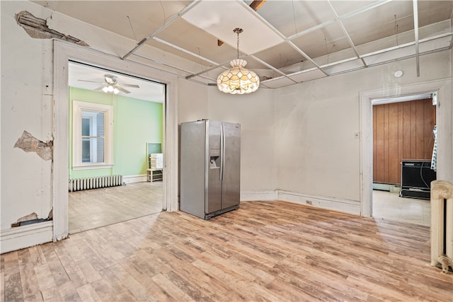 unfurnished dining area featuring a baseboard heating unit, ceiling fan, radiator heating unit, and wood finished floors