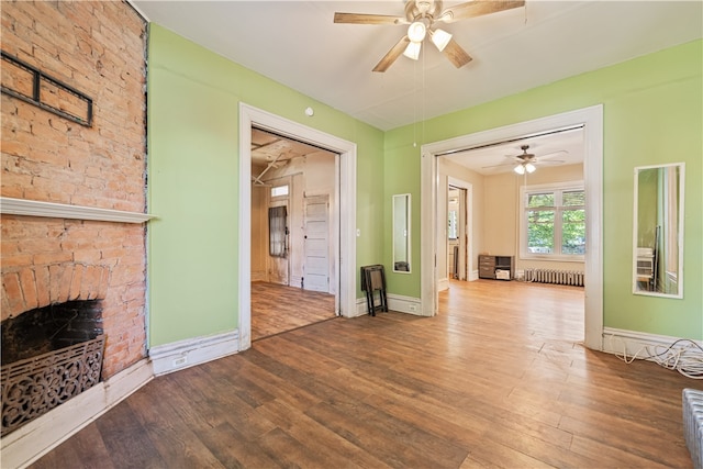 interior space featuring radiator, a fireplace, baseboards, and wood finished floors