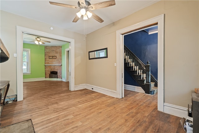 living area with stairs, a fireplace, baseboards, and wood finished floors