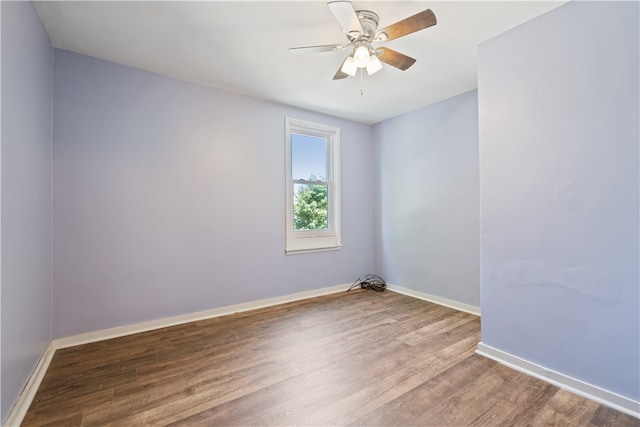 spare room with wood finished floors, a ceiling fan, and baseboards