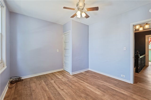 unfurnished room featuring ceiling fan, wood finished floors, and baseboards