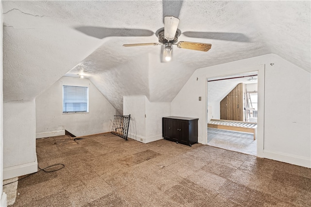 additional living space featuring a textured ceiling, baseboards, vaulted ceiling, and carpet flooring