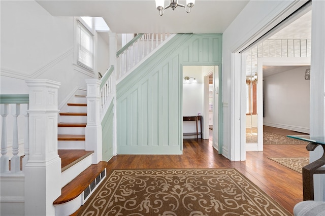 stairway featuring a chandelier, hardwood / wood-style floors, and ornate columns