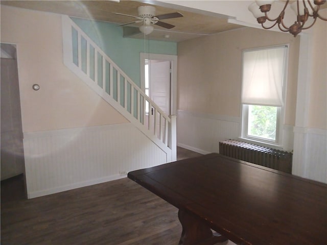 stairway with radiator, hardwood / wood-style floors, and ceiling fan with notable chandelier