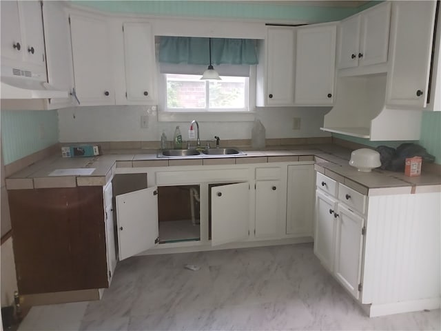 kitchen with hanging light fixtures, sink, white cabinets, and light tile patterned flooring