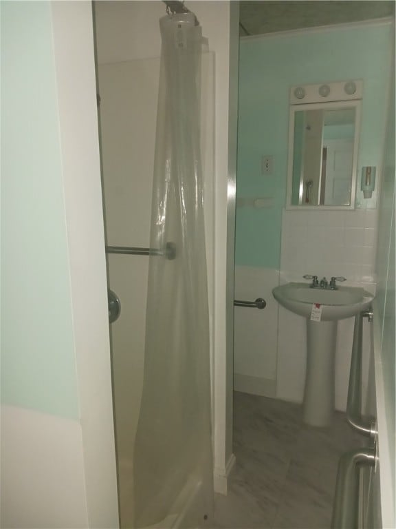 bathroom with curtained shower, sink, and tasteful backsplash