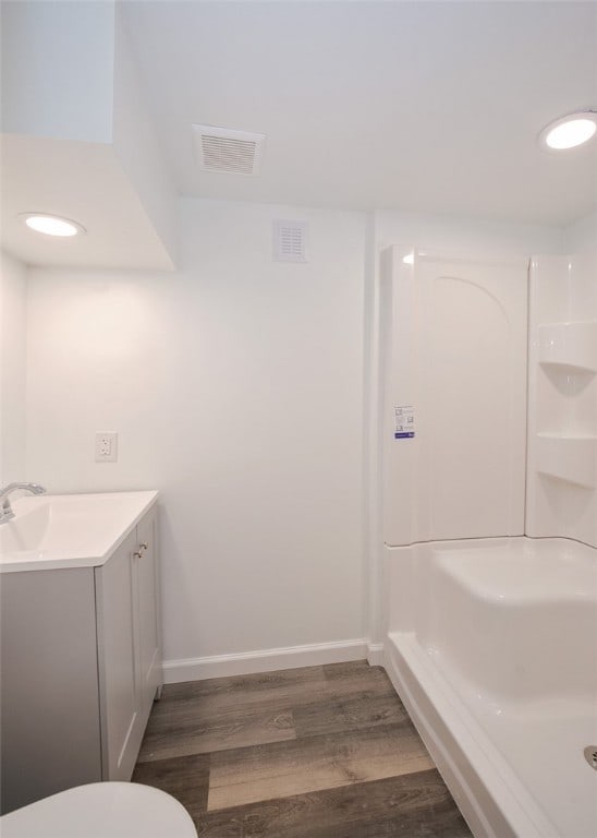 bathroom featuring wood-type flooring, vanity, toilet, and a shower