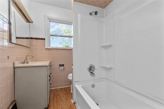 full bathroom with toilet, vanity, shower / bath combination, tile walls, and hardwood / wood-style flooring