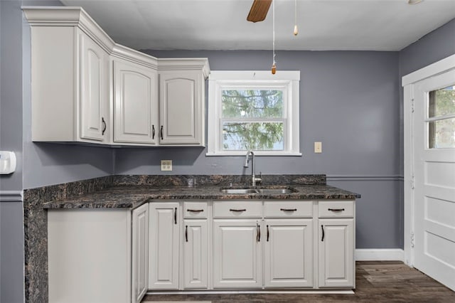 kitchen featuring dark stone countertops, dark wood-type flooring, sink, white cabinetry, and ceiling fan