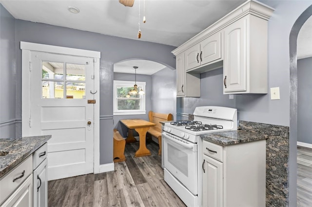 kitchen with dark stone counters, white cabinetry, white gas range, and light hardwood / wood-style floors