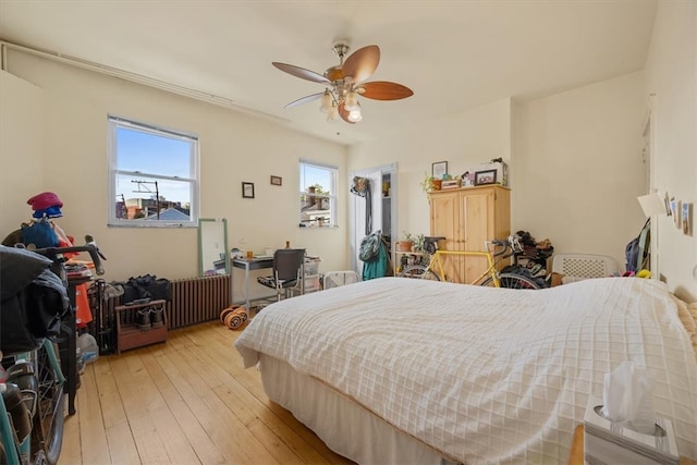 bedroom with radiator, light hardwood / wood-style flooring, and ceiling fan