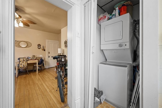 clothes washing area featuring stacked washer and clothes dryer, ceiling fan, and light hardwood / wood-style flooring