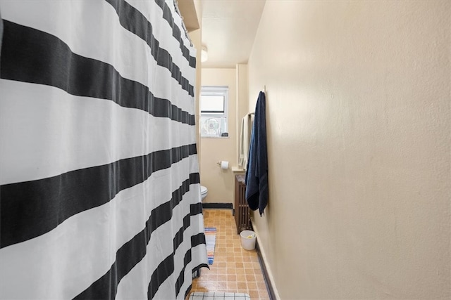 bathroom featuring radiator, toilet, curtained shower, and tile patterned flooring