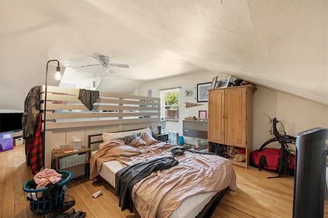 bedroom with ceiling fan, light hardwood / wood-style floors, and vaulted ceiling