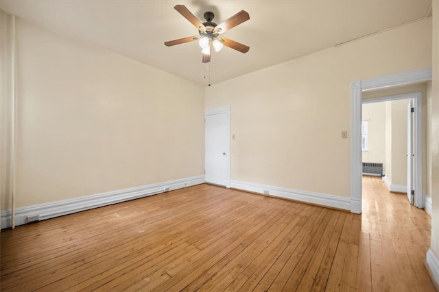 unfurnished room featuring ceiling fan, radiator heating unit, and light hardwood / wood-style flooring