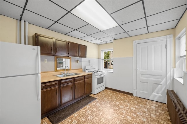 kitchen featuring a paneled ceiling, white appliances, light tile patterned flooring, and sink