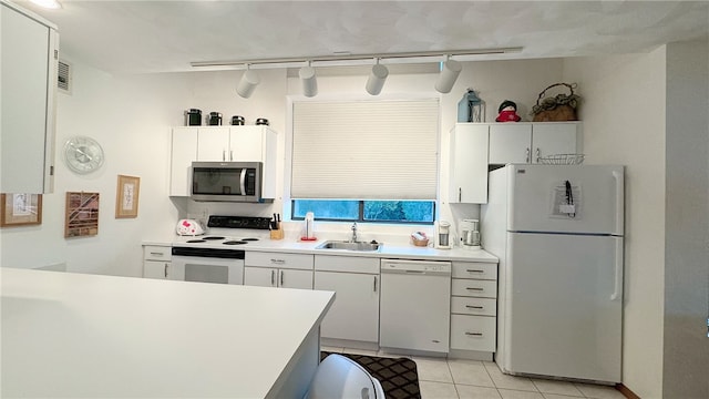 kitchen with light tile patterned flooring, white appliances, sink, white cabinetry, and track lighting