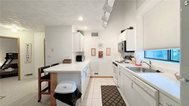 kitchen with white cabinets, white appliances, light colored carpet, and sink