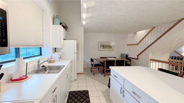 kitchen featuring track lighting, white cabinetry, sink, hanging light fixtures, and light tile patterned flooring